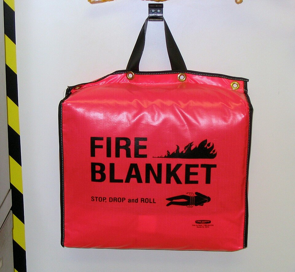 A red fire blanket in a wall-hung bag