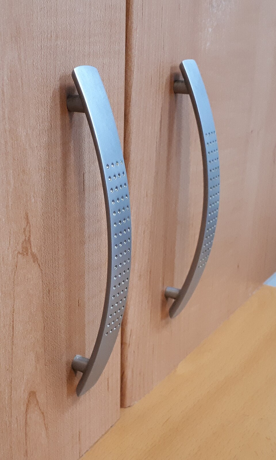 Brushed metal bar handles on kitchen cupboard doors