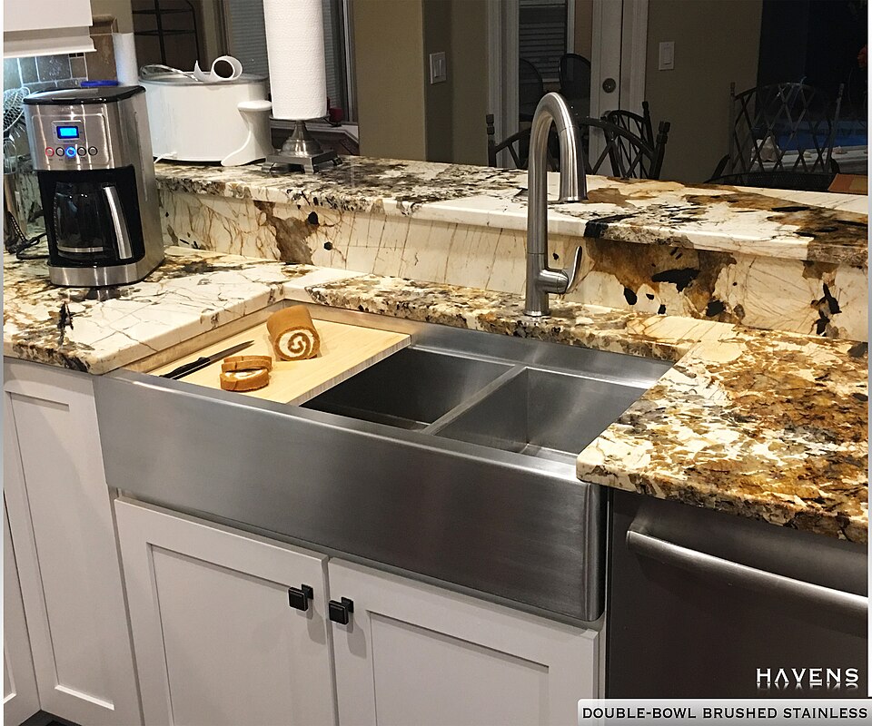 A brushed stainless steel double-bowl sink set into a granite worktop