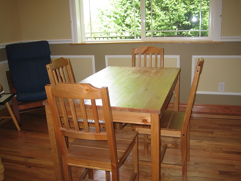 A wooden kitchen table with four chairs below a window