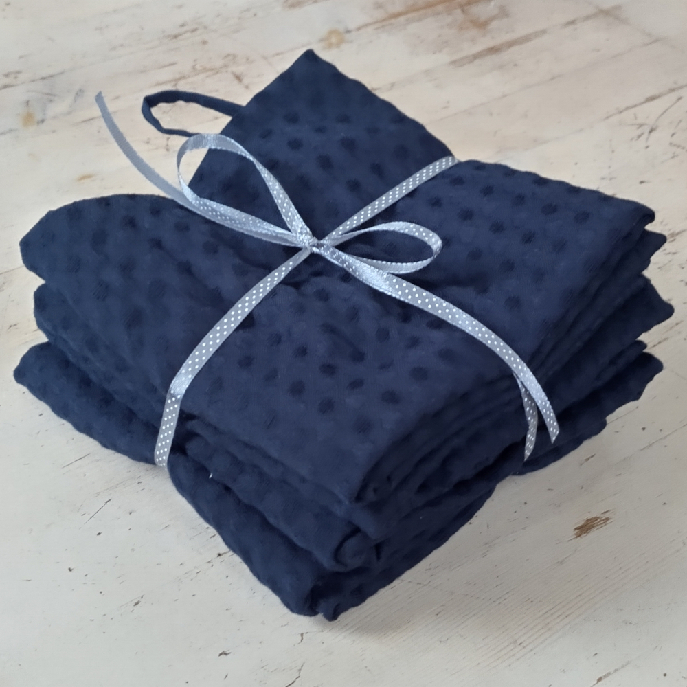 A stack of dark blue tea towels tied with ribbon