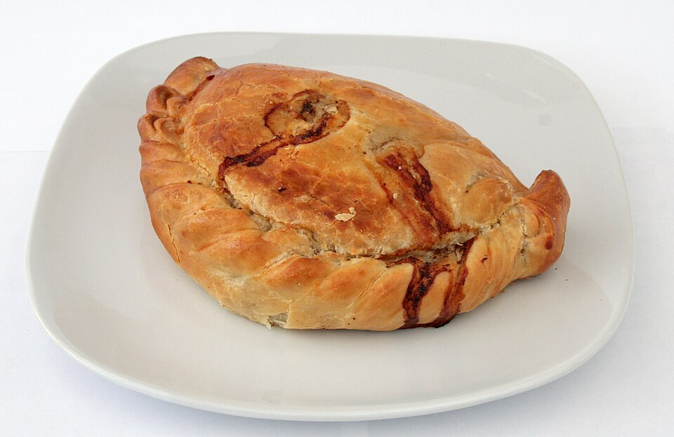A golden, crimped Cornish pasty on a plate