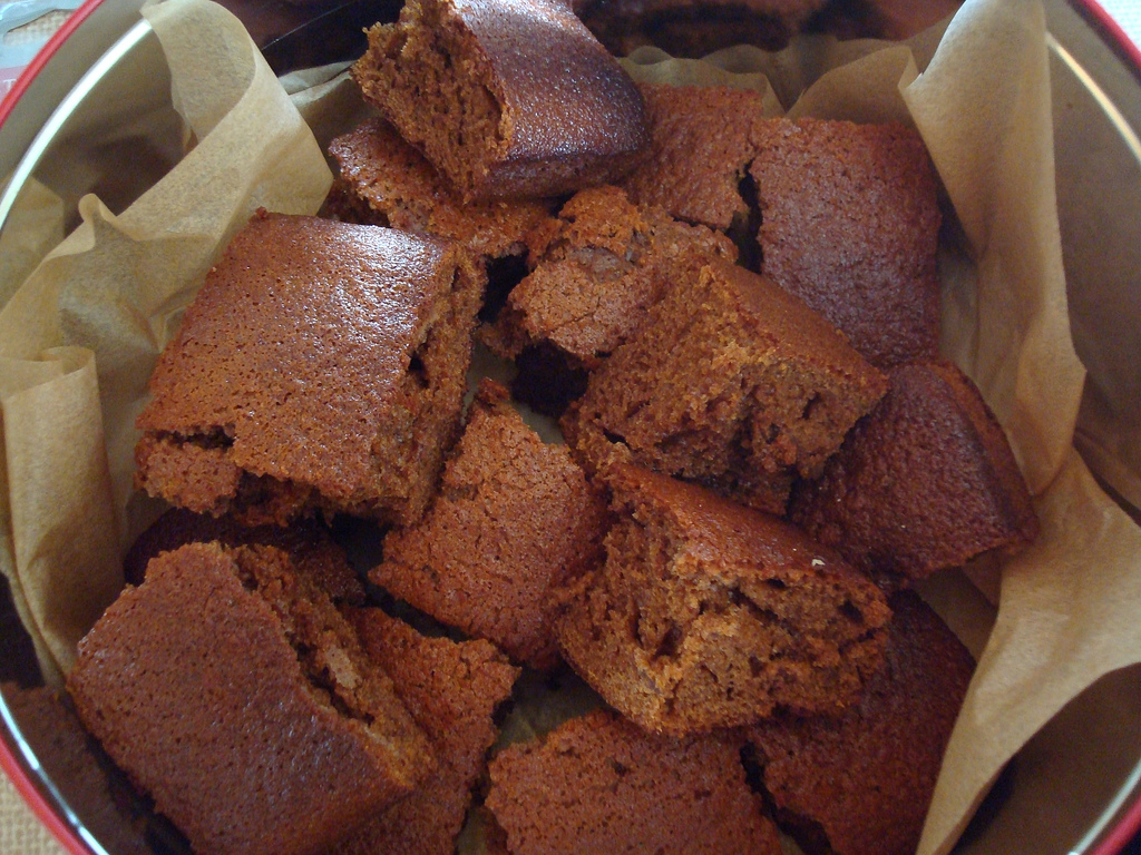 Squares of dark, sticky Yorkshire parkin in a paper-lined tin