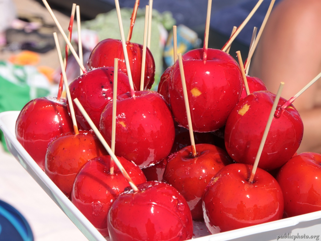 A tray of glossy red toffee apples on wooden sticks