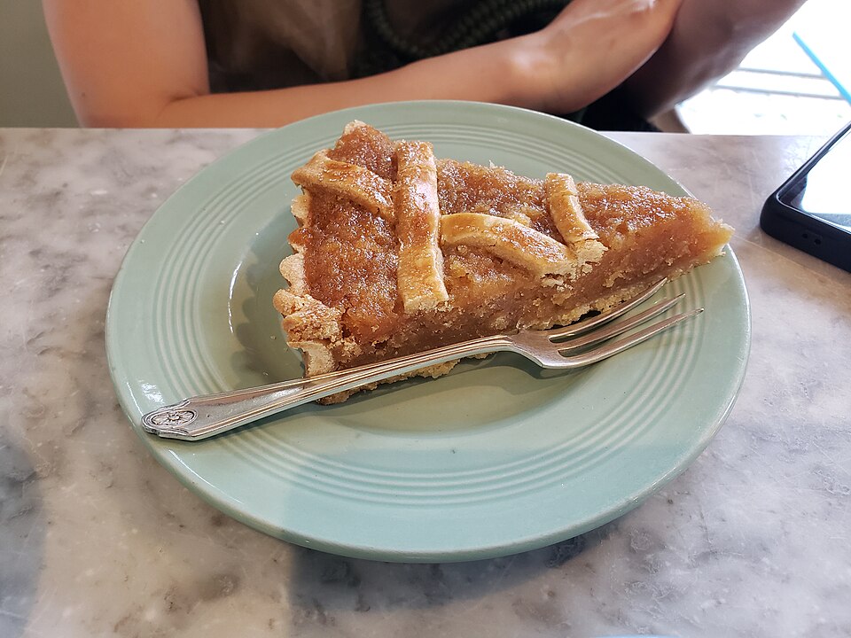 A slice of treacle tart with a lattice top on a green plate