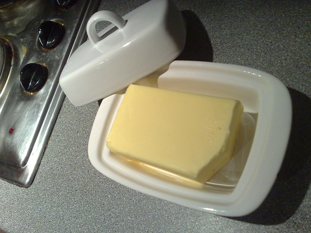 A white lidded butter dish with a block of butter