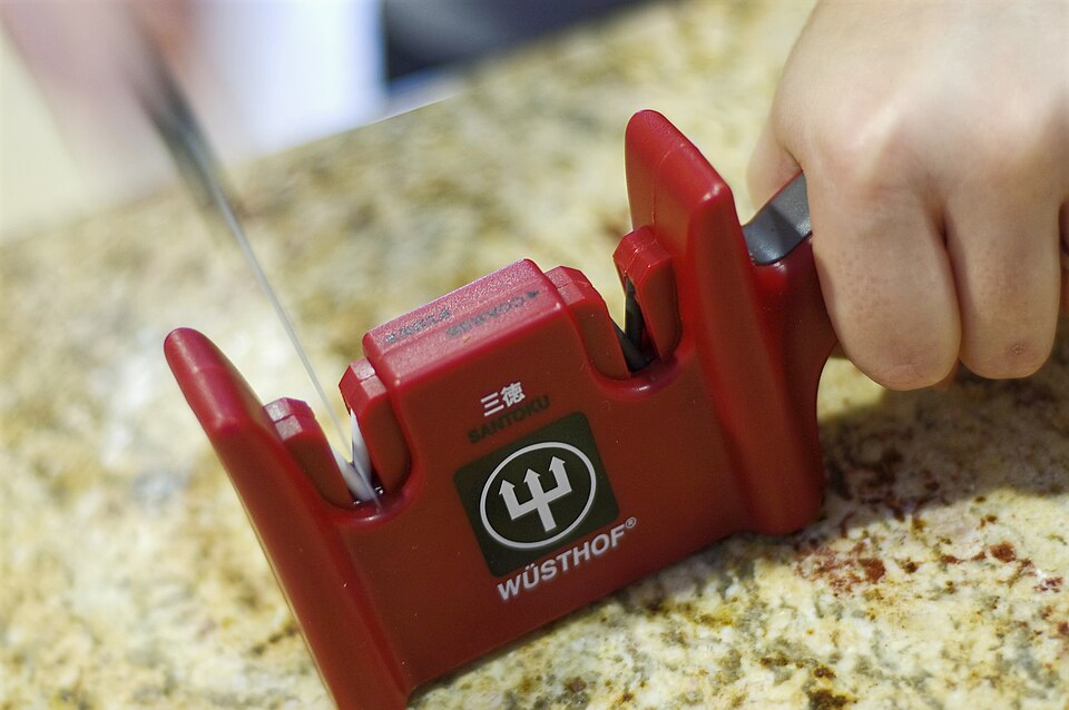 A knife being drawn through a pull-through sharpener