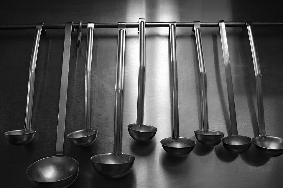 A row of stainless steel serving ladles