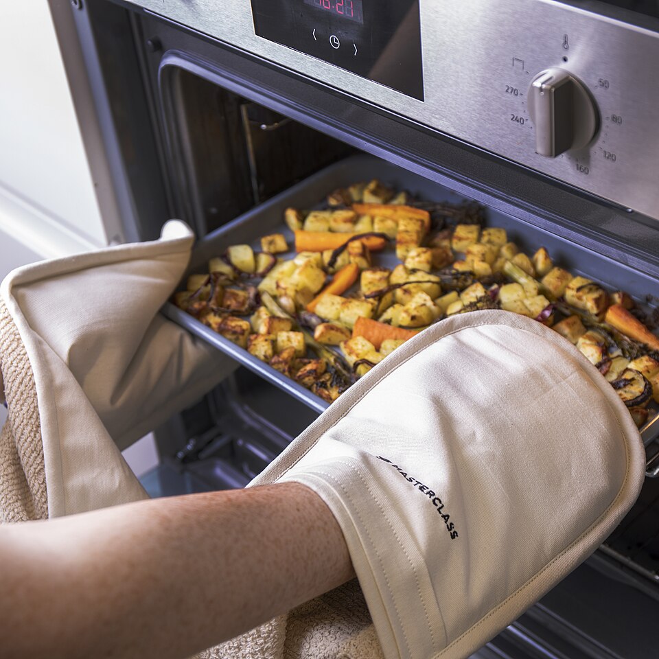 Oven gloves being used to lift a tray from the oven