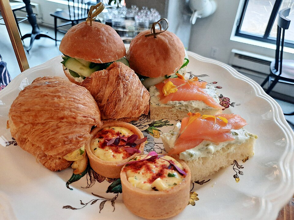 An afternoon tea stand with sandwiches, pastries and quiches
